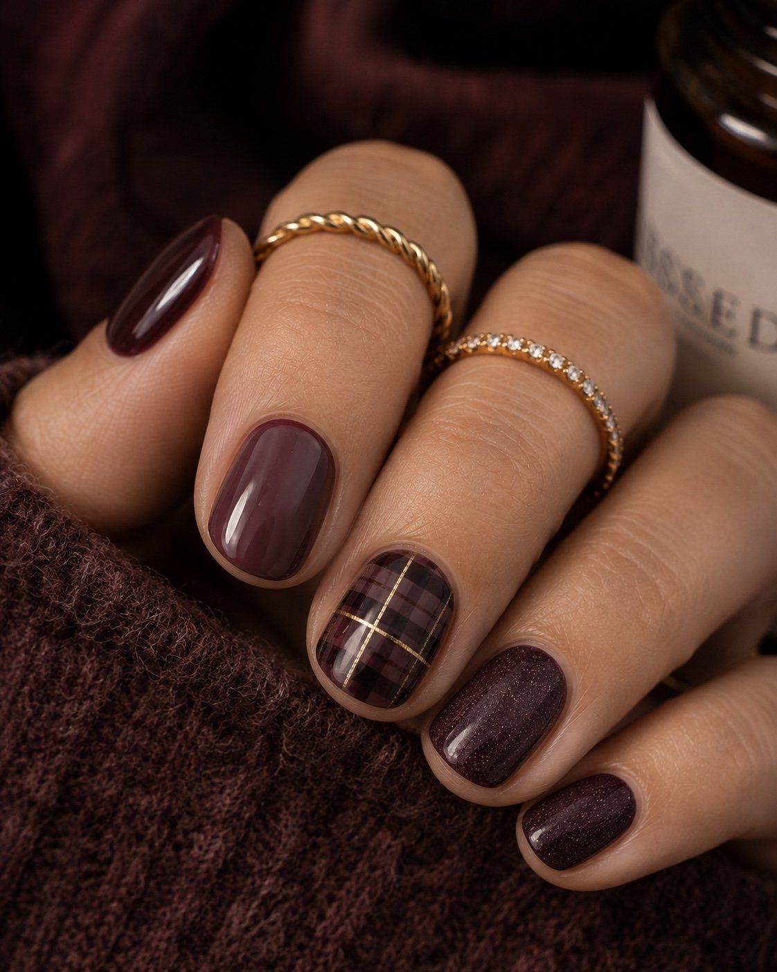 Short burgundy and smoky plum nails with one fine gold plaid accent nail