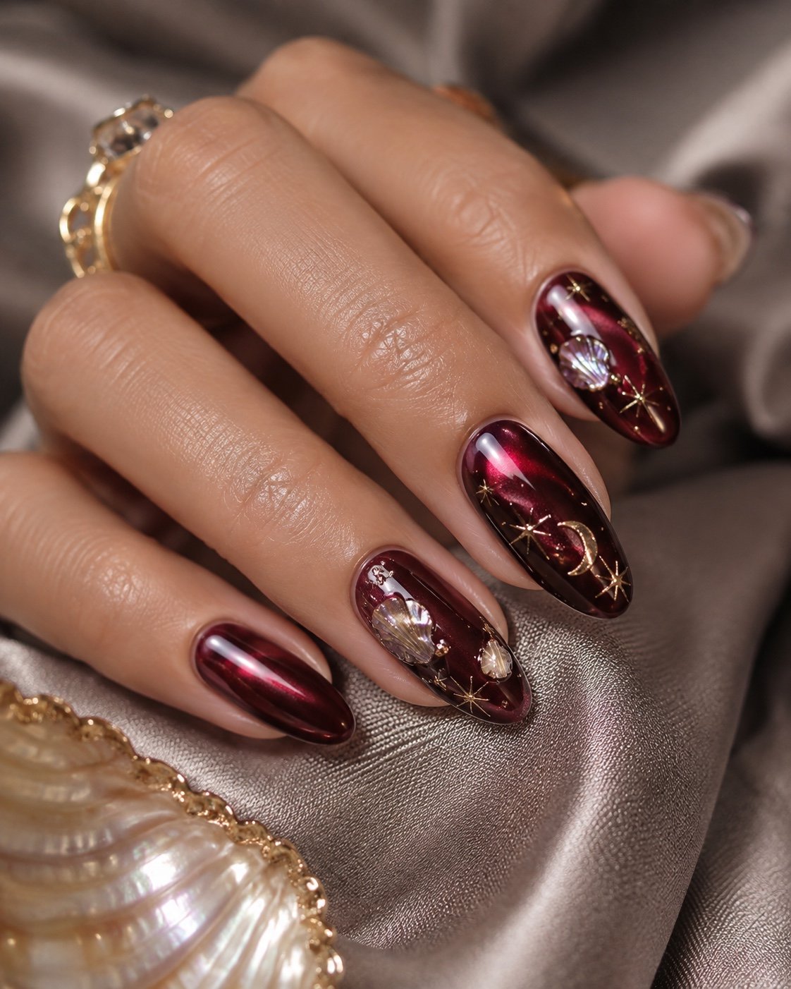 Black cherry jelly almond nails with gold moons, stars and shell accents