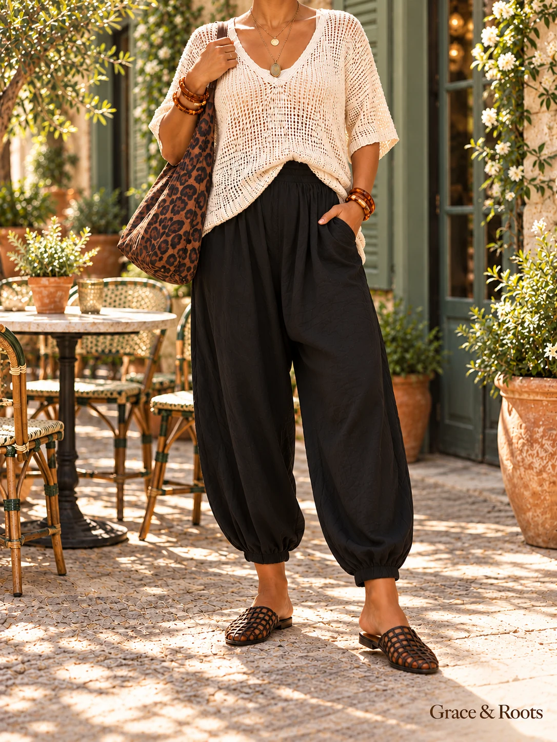 Faceless boho outfit with an ivory open-knit top, black draped ankle pants, leopard hobo bag, amber bracelets, and tortoiseshell lattice flats.